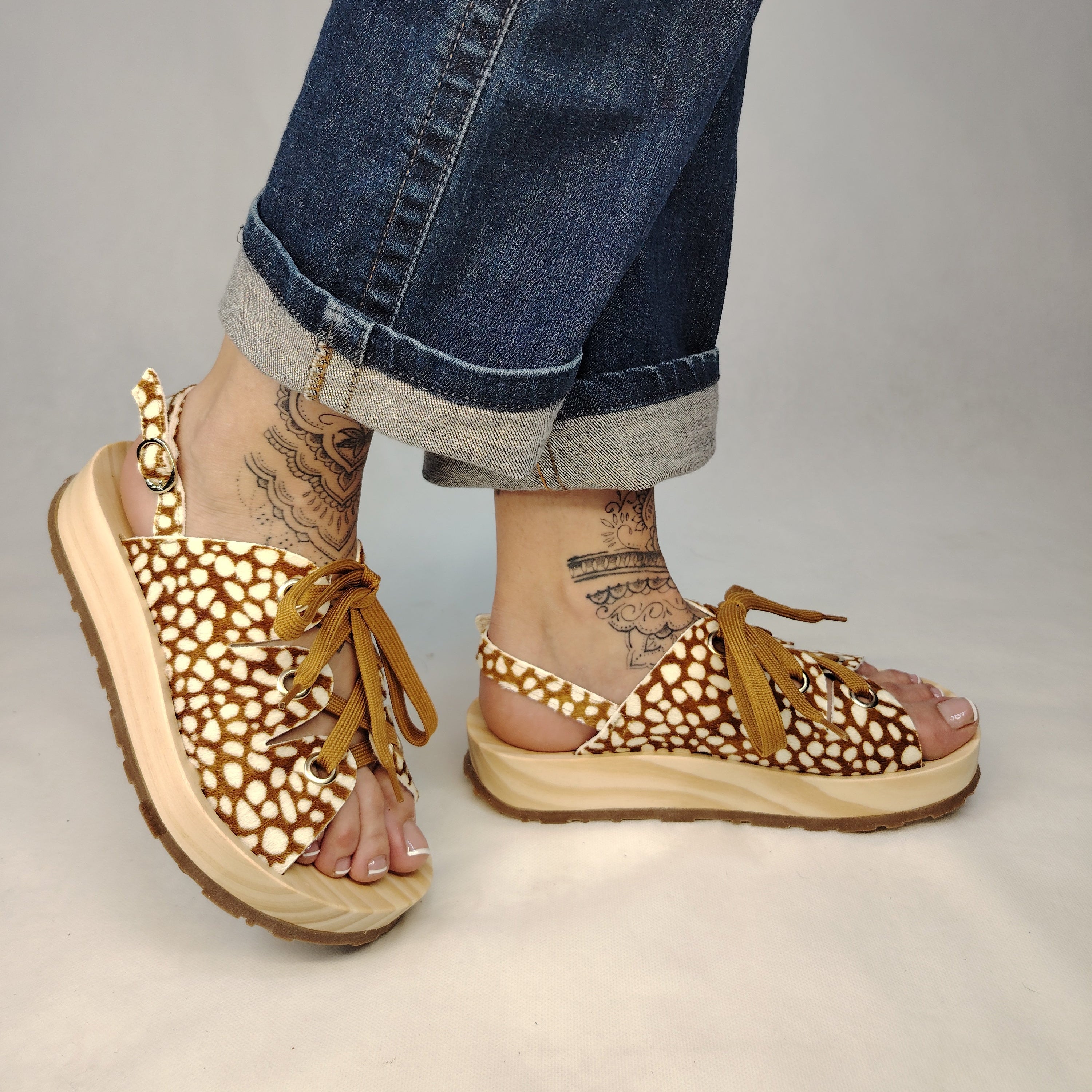 Sandalias de plataforma de madera natural artesanal con tira trasera y pala de piel efecto pelo con estampado de cervatillo y cordones marrones.