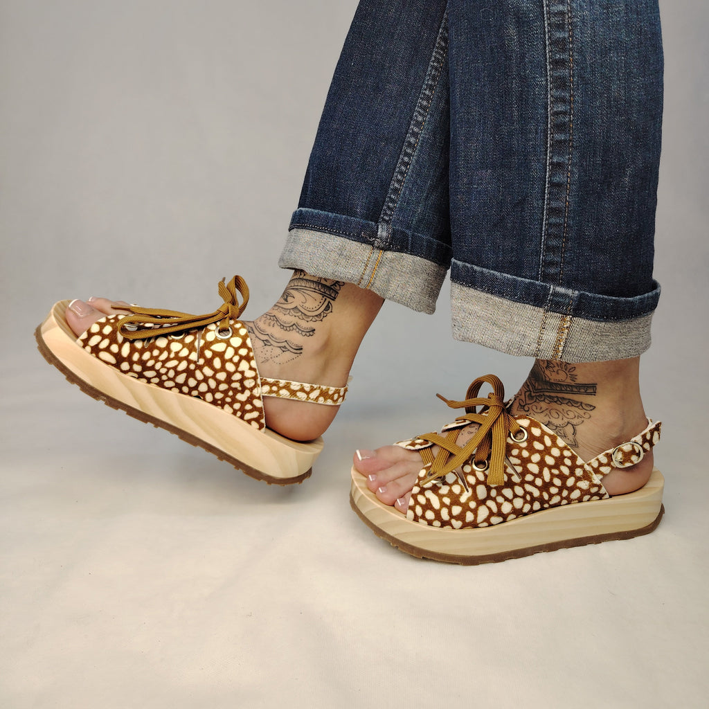 Sandalias de plataforma de madera natural artesanal con tira trasera y pala de piel efecto pelo con estampado de cervatillo y cordones marrones.