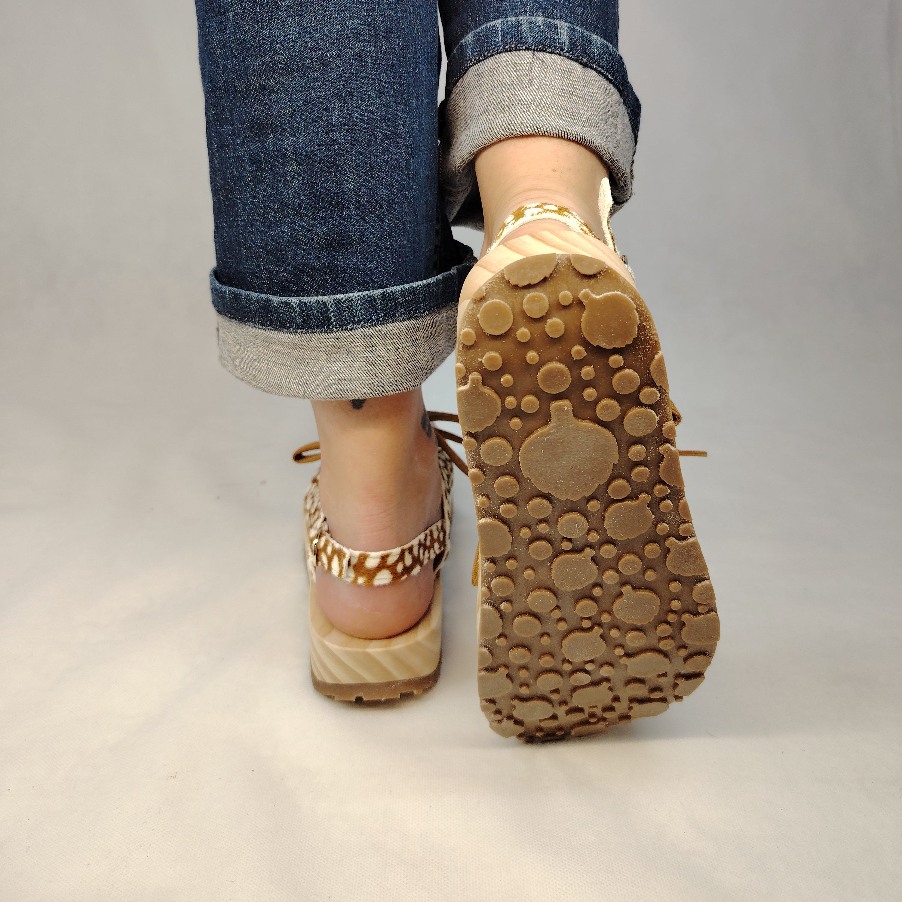Sandalias de plataforma de madera natural artesanal con tira trasera y pala de piel efecto pelo con estampado de cervatillo y cordones marrones.