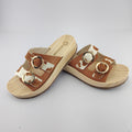 Sandalias tipo zueco de la marca Artichoke con base de madera, dos correas ajustables de cuero y piel sintética de estampado animal print de vaca, y hebillas redondas de metal dorado.