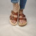 Sandalias tipo zueco de la marca Artichoke con base de madera, dos correas ajustables de cuero y piel sintética de estampado Marrón, y hebillas redondas de metal dorado.