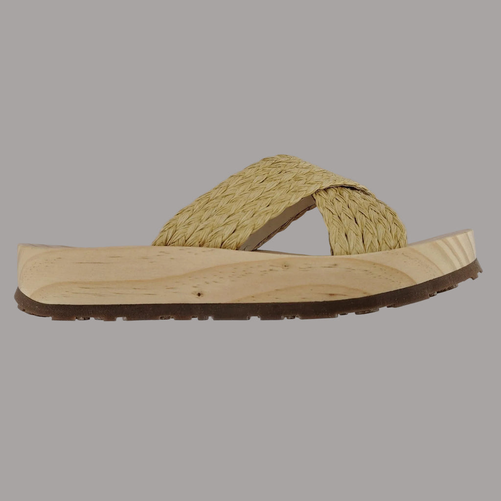 Sandalia plana de madera natural con tiras cruzadas de rafia trenzada en color natural y diseño artesanal de verano.