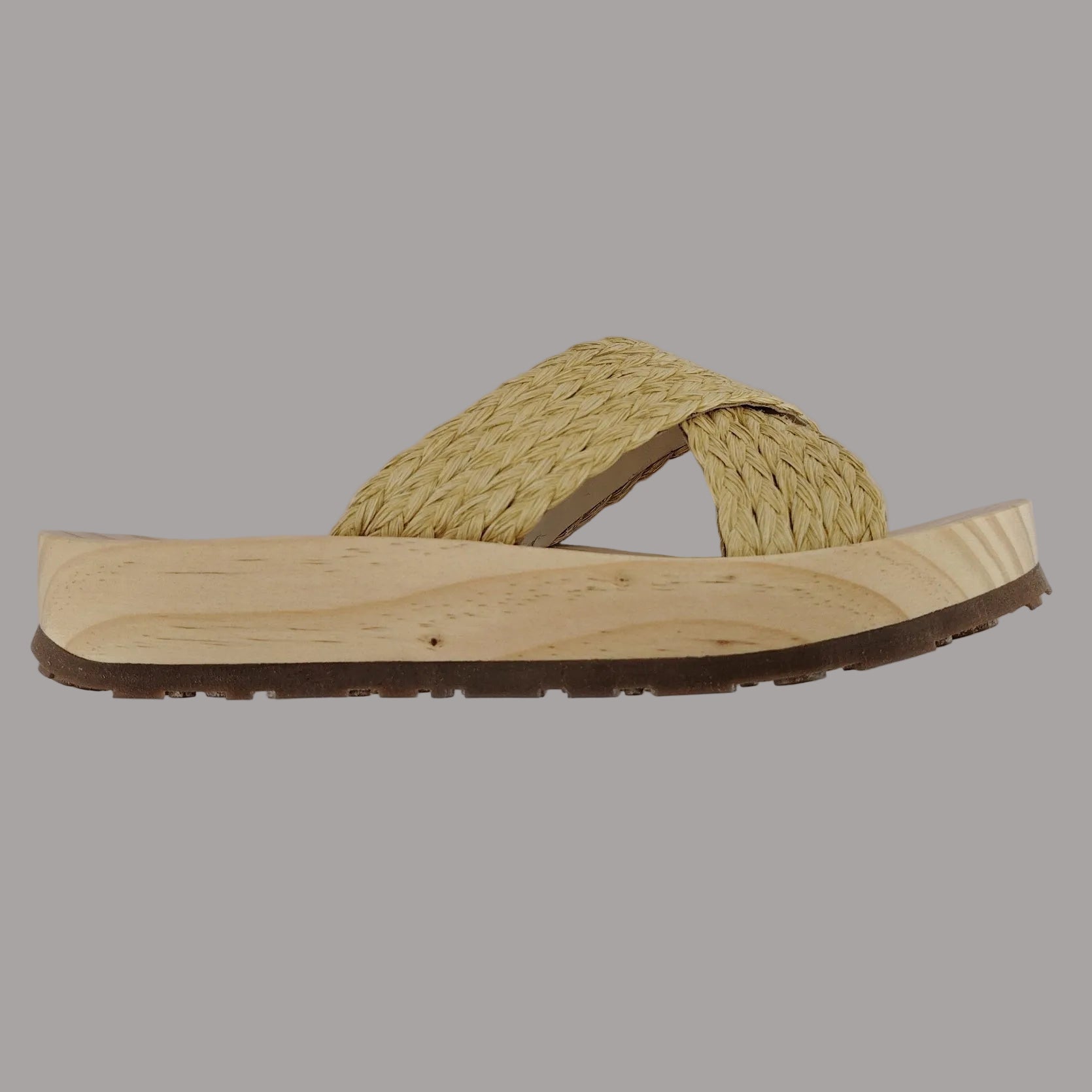 Sandalia plana de madera natural con tiras cruzadas de rafia trenzada en color natural y diseño artesanal de verano.