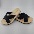 Sandalia plana de madera natural con tiras cruzadas de yute trenzada en color negro y diseño artesanal de verano.