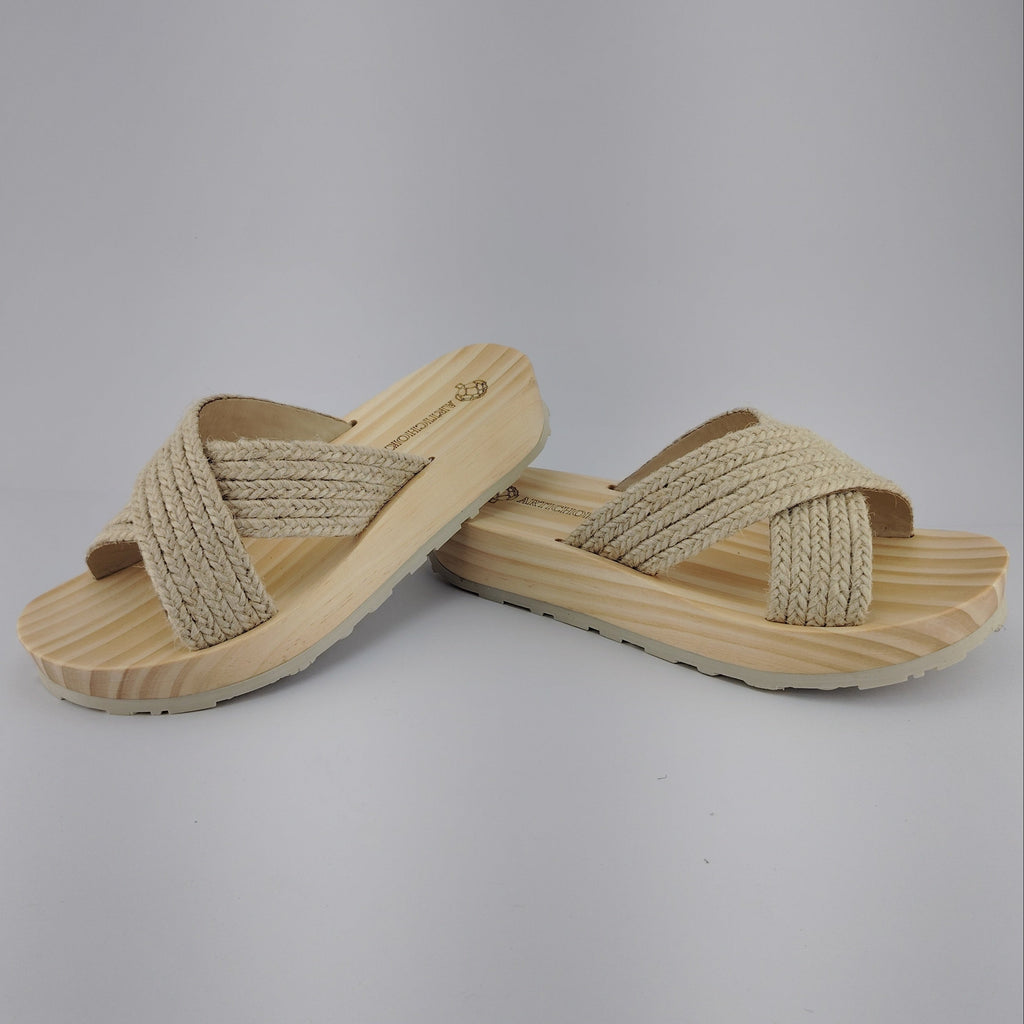 Sandalia plana de madera natural con tiras cruzadas de yute trenzada en color natural y diseño artesanal de verano.