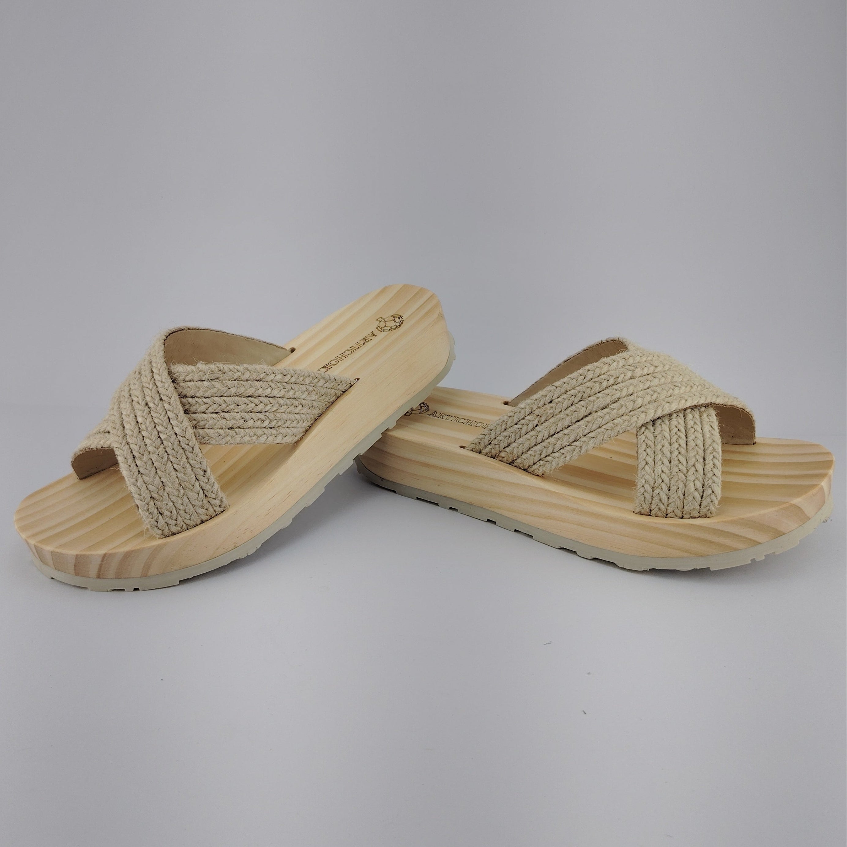 Sandalia plana de madera natural con tiras cruzadas de yute trenzada en color natural y diseño artesanal de verano.