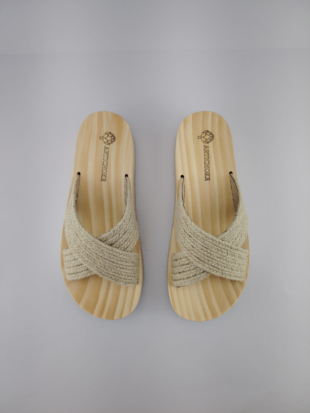 Sandalia plana de madera natural con tiras cruzadas de yute trenzada en color natural y diseño artesanal de verano.