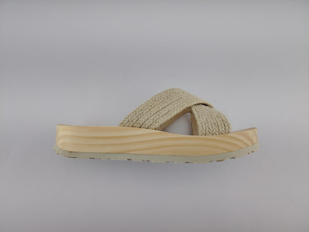 Sandalia plana de madera natural con tiras cruzadas de yute trenzada en color natural y diseño artesanal de verano.