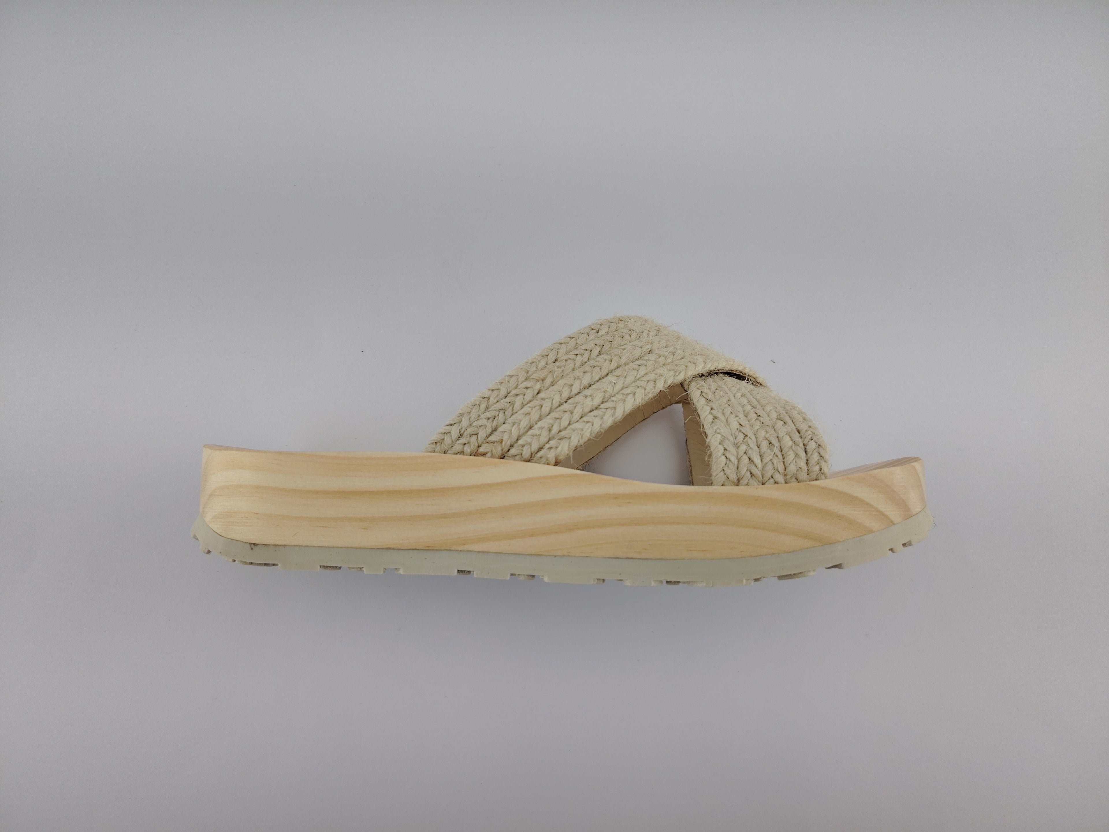 Sandalia plana de madera natural con tiras cruzadas de yute trenzada en color natural y diseño artesanal de verano.