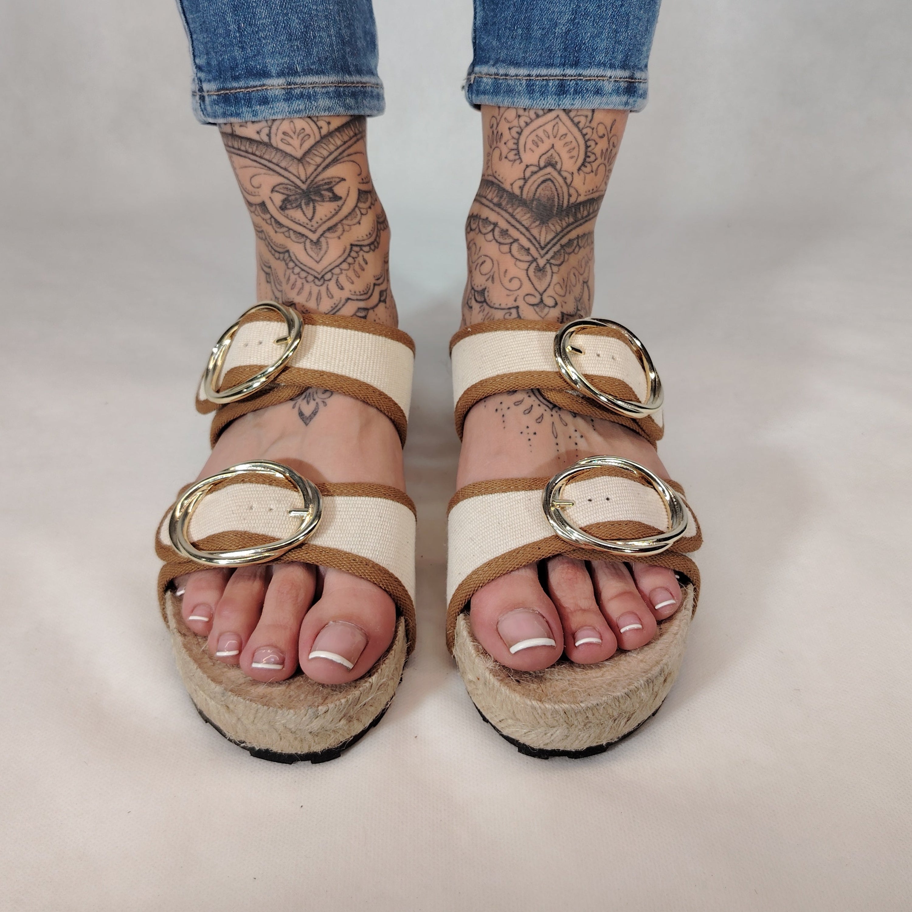 Sandalia plana de yute natural con corte en tejido color blanco y detalles en cuero con 2 hebillas y diseño artesanal de verano.
