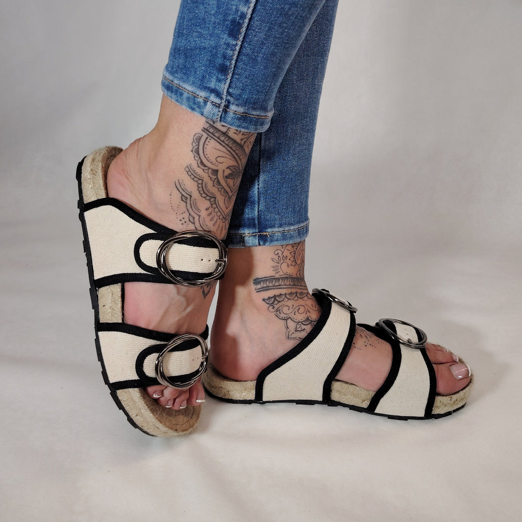Sandalia plana de yute natural con corte en tejido color blanco y detalles en negro con 2 hebillas y diseño artesanal de verano.