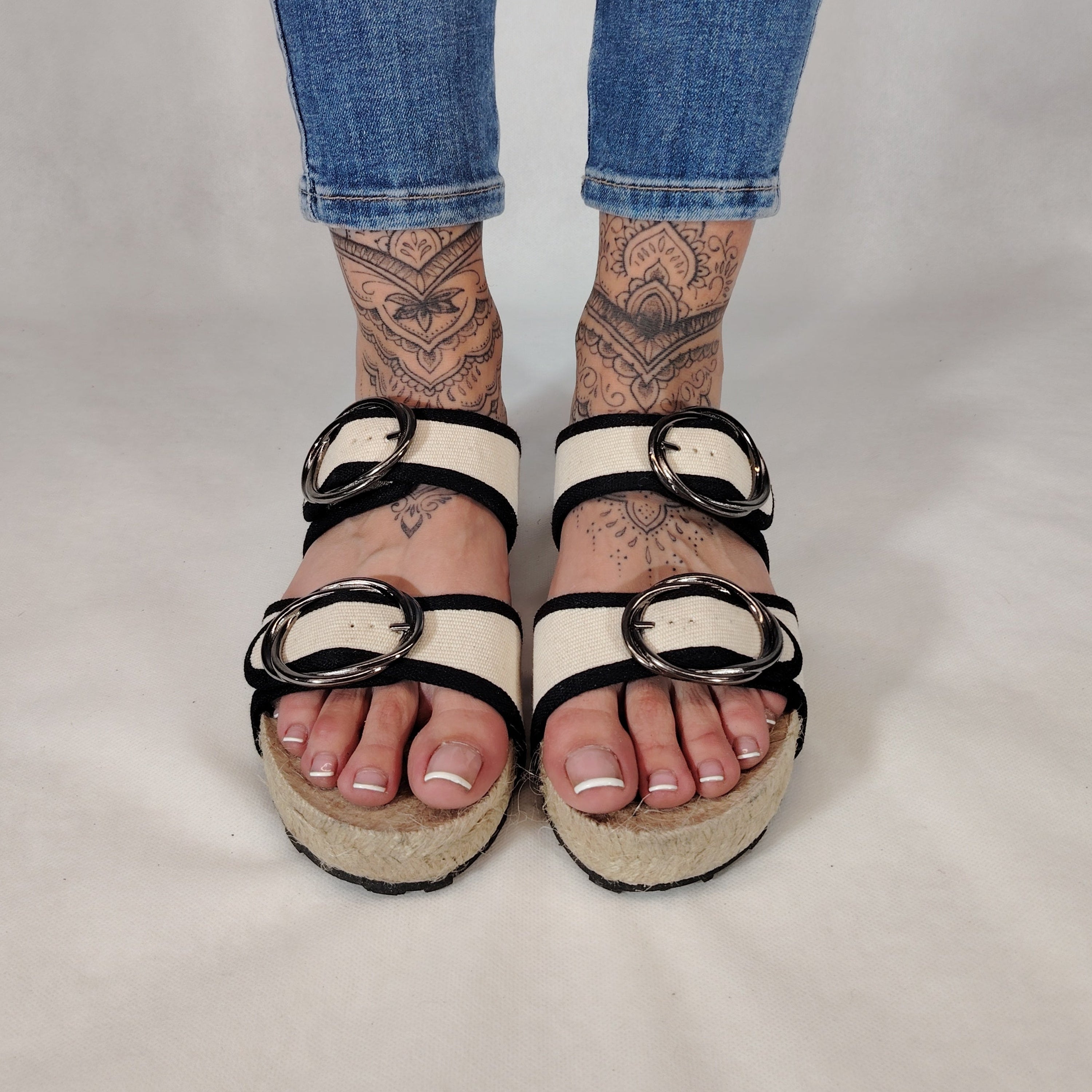 Sandalia plana de yute natural con corte en tejido color blanco y detalles en negro con 2 hebillas y diseño artesanal de verano.