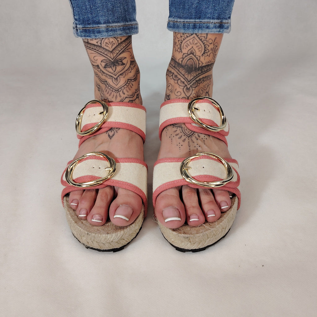 Sandalia plana de yute natural con corte en tejido color blanco y detalles en rosa con 2 hebillas y diseño artesanal de verano.
