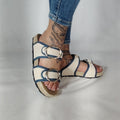 Sandalia plana de yute natural con corte en tejido color blanco y detalles en azul con 2 hebillas y diseño artesanal de verano.