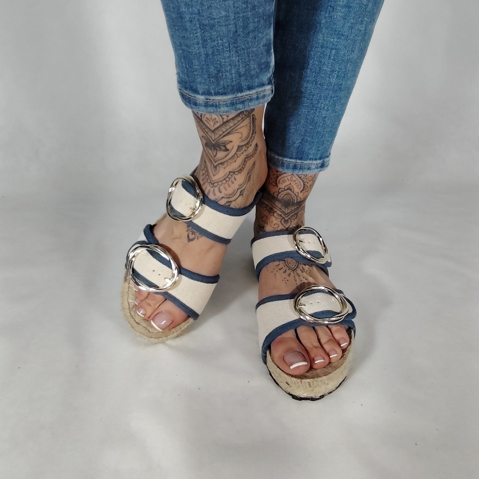 Sandalia plana de yute natural con corte en tejido color blanco y detalles en azul con 2 hebillas y diseño artesanal de verano.