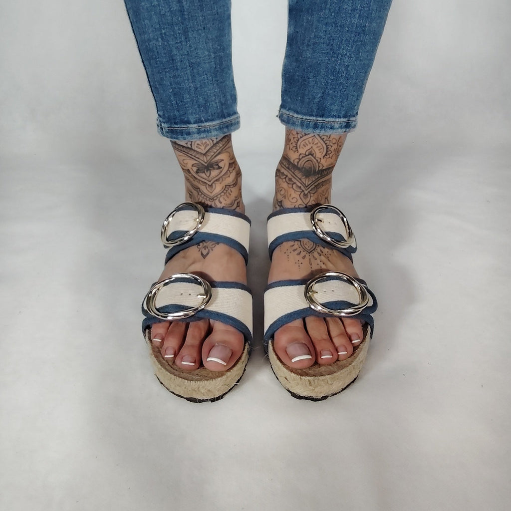 Sandalia plana de yute natural con corte en tejido color blanco y detalles en azul con 2 hebillas y diseño artesanal de verano.