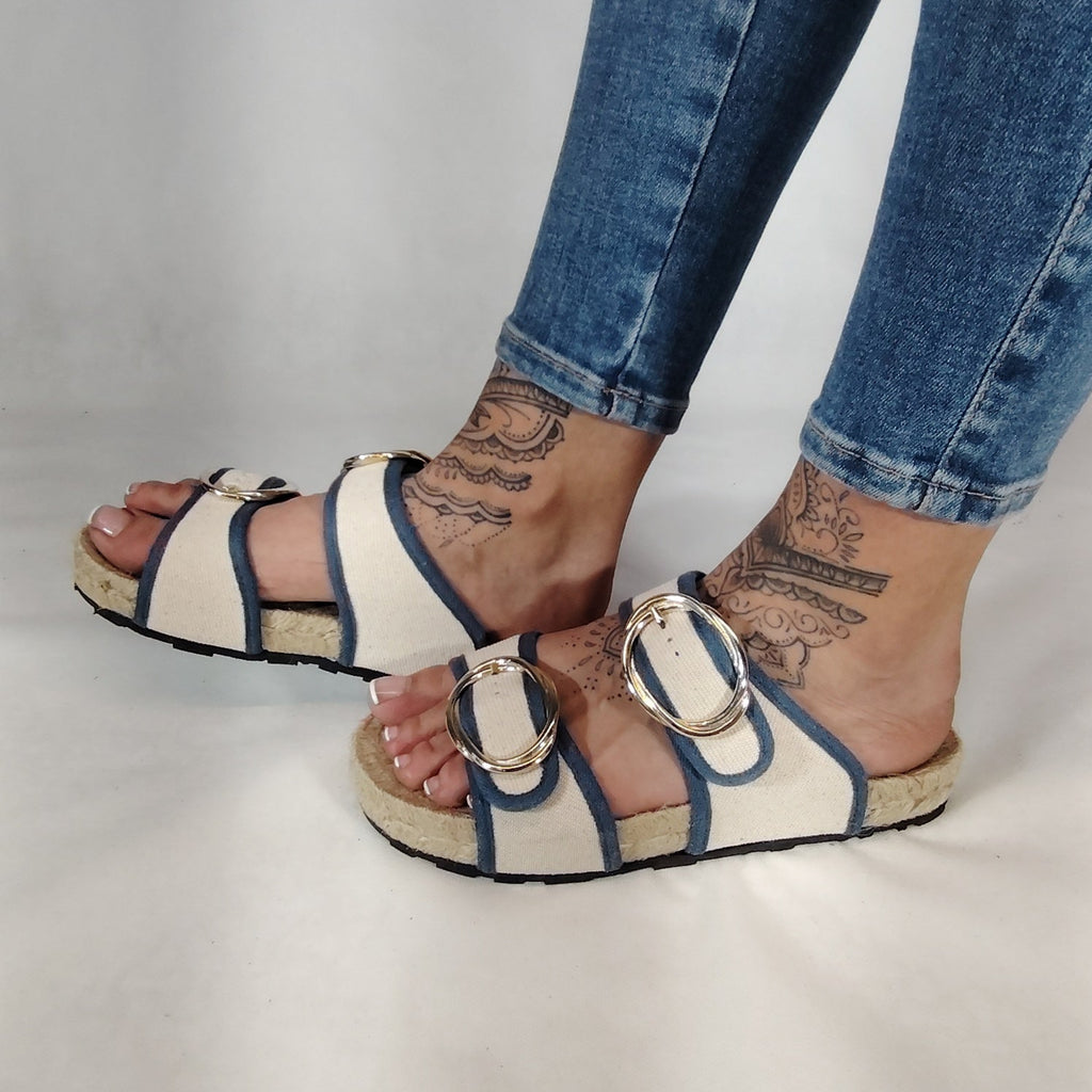 Sandalia plana de yute natural con corte en tejido color blanco y detalles en azul con 2 hebillas y diseño artesanal de verano.